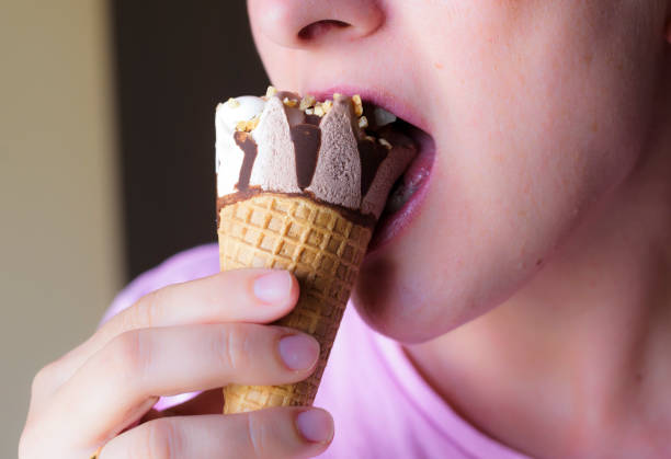 istock woman's mouth eating chocolate ice cream and cream with almonds 1161436112