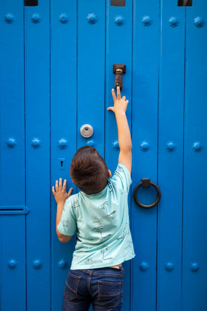 Little boy trying to knock a blue door