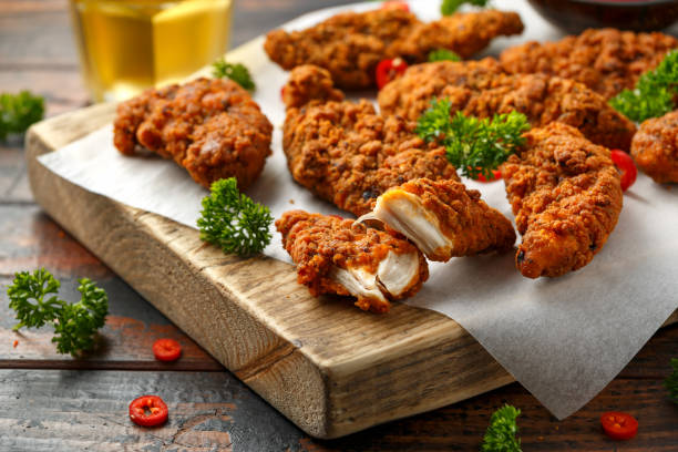 Breaded chicken strips with beer, ketchup and mayonnaise on wooden board Breaded chicken strips with beer, ketchup and mayonnaise on wooden board. nuggets heat stock pictures, royalty-free photos & images