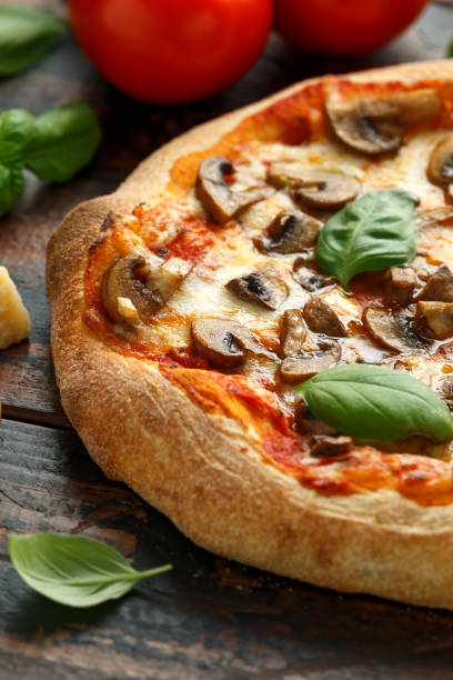 istock Hot Mushroom Pizza with basil, tomatoes, mozzarella and parmesan cheese on wooden table. ready to eat. vegetarian food 1161443682