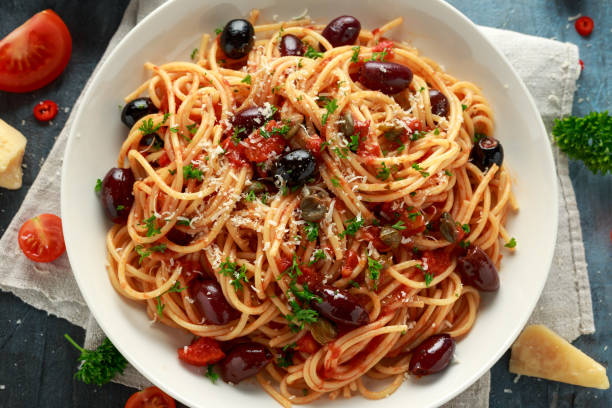 pasta alla puttanesca with garlic, olives, capers, tomato and anchois fish - caper sauce imagens e fotografias de stock