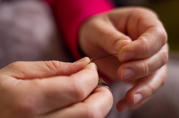 istock Woman cutting and knotting a thread on a needle 1161445778