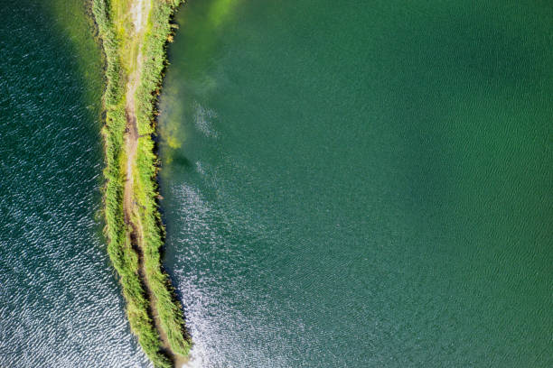 istock A small spit with a path covered with green grass on both sides, on a clear lake. Aerial photography 1161445809