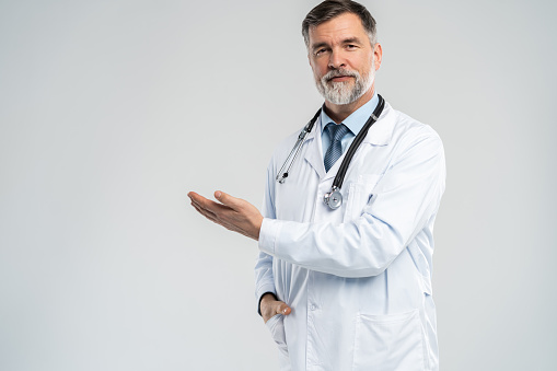 Doctor senior man, medical professional holding something in empty hand isolated over white background