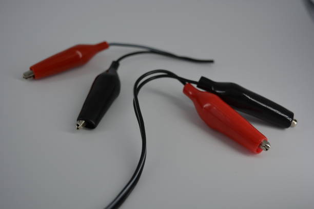 istock Electrical wire with red and black connectors for connecting to a power source, plus and minus from the mains, battery. Metal crocodiles in a tight rubber shell for a safe and comfortable electrical connection. 1161446158