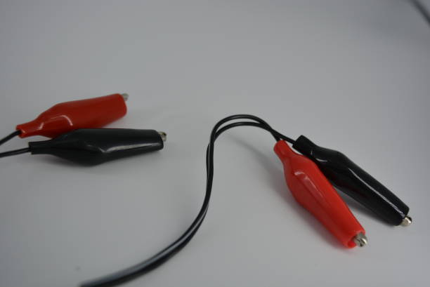 istock Electrical wire with red and black connectors for connecting to a power source, plus and minus from the mains, battery. Metal crocodiles in a tight rubber shell for a safe and comfortable electrical connection. 1161446162