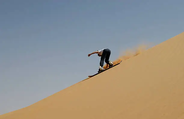 Riding a Snowboard on a large dune in the Sahara.