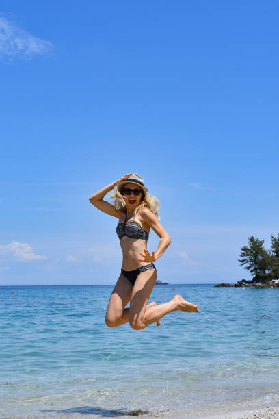 istock blonde woman jumping on the beach 1161447052