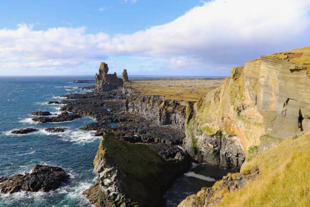 istock Rock and lava formations along the coastline and the Londrangar basalt cliffs on the southern coast of Snaefellsnes peninsula in West Iceland. The Londrangar basalt cliffs - huge towers of lava. 1161452310