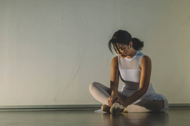 an asian chinese female teenager hurt her leg during practise in her ballet studio and sit on the floor with pain an asian chinese female teenager hurt her leg during practise in her ballet studio and sit on the floor with pain ballet dancer feet stock pictures, royalty-free photos & images
