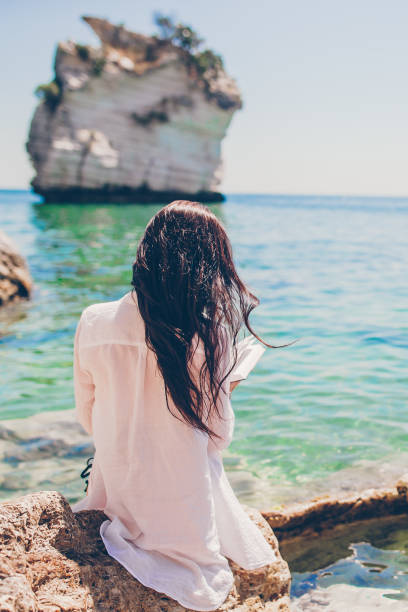 istock Young woman reading on tropical white beach 1161455125