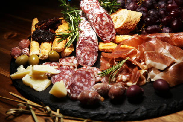 istock antipasto various appetizer. Cutting board with prosciutto, salami, cheese, bread and olives on dark wooden background 1161458068
