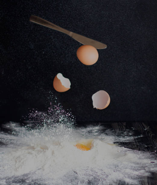 istock Eggs are broken and fall into flour on a black background. 1161458261