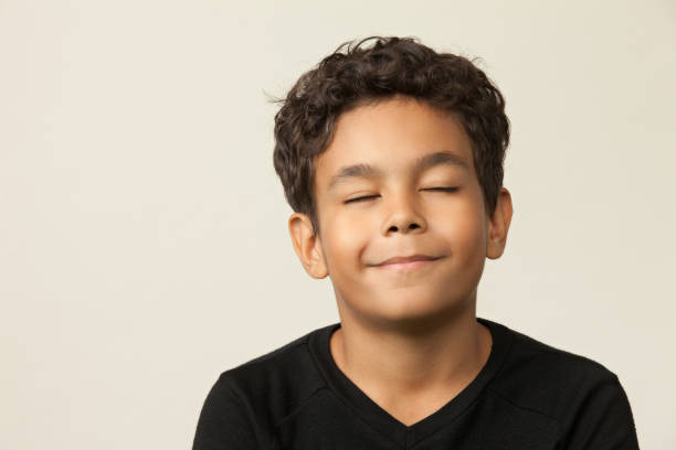 retrato de estudio de primer plano de un niño de 12 años sobre un fondo beige - ojos cerrados fotografías e imágenes de stock