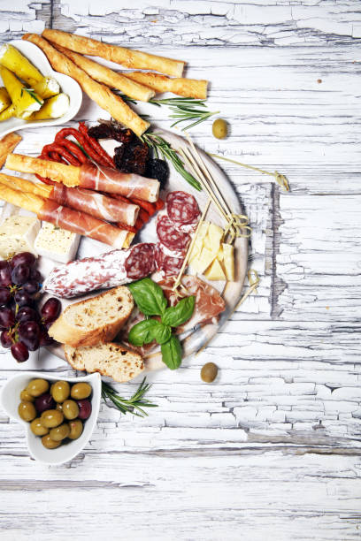 istock antipasto various appetizer. Cutting board with prosciutto, salami, cheese, bread and olives on white wooden background 1161459934
