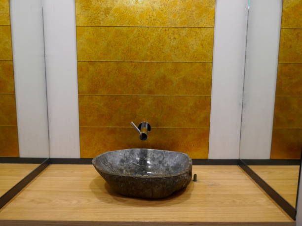 lavabo en pierre naturelle grise sur un lave-linge en bois devant le revêtement de mur texturé brillant d'or et le fond blanc - washstand photos et images de collection