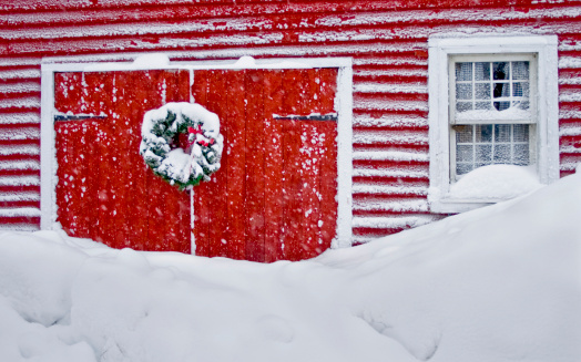 Christmas wreath on a barn door in a winter snowstorm.