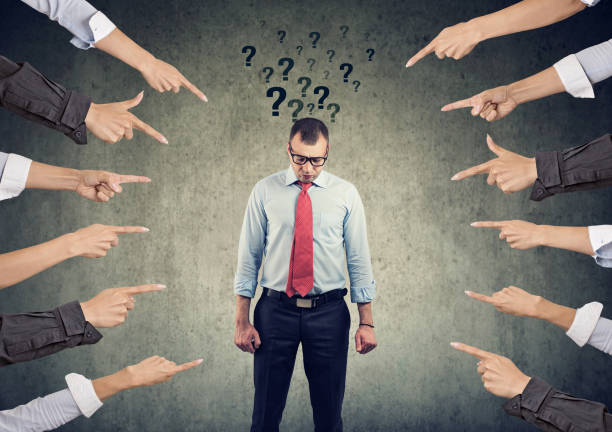 istock Sad man with questions looking down with many fingers pointing at him 1161469441