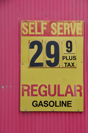 An old weathered sign at a defunct gas station showing the price for regular of decades ago