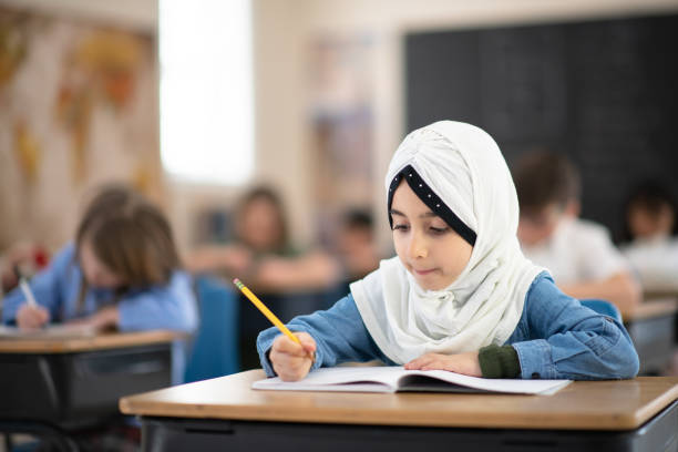 istock Muslim Girl Writing in her Notebook in Class 1161475953