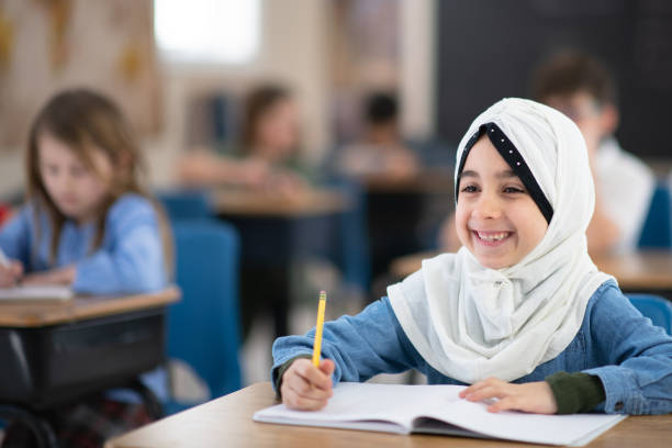 istock Muslim Girl Writing in her Notebook in Class 1161475954
