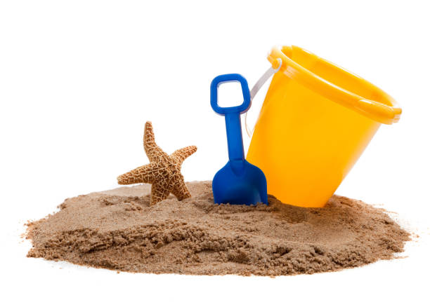 Yellow Bucket on a beach with a blue shovel and starfish stock photo