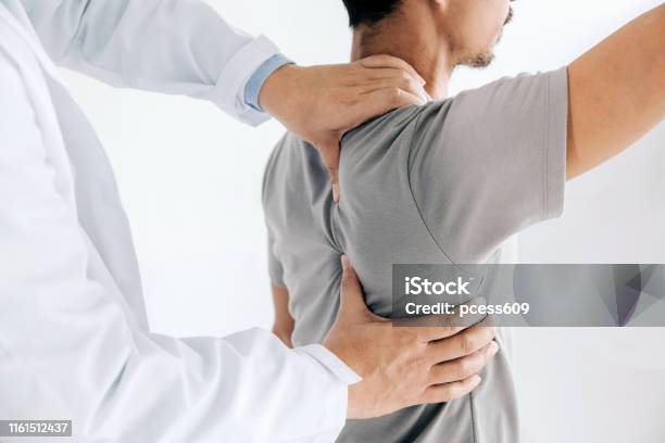 理学療法士は男性の背中に癒しの治療を行います腰痛患者治療医師マッサージセラピストオフィス症候群 - 肩のストックフォトや画像を多数ご用意