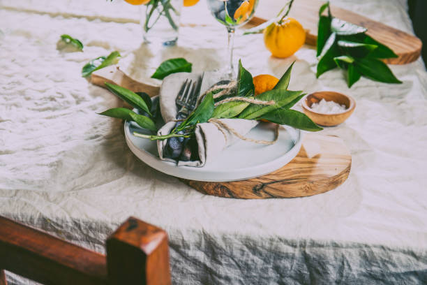 istock Table setting with white plate, cutlery, linen napkin and orange tree branch decoration on white linen tablecloth . Close up. Table with table setting and shair 1161516826