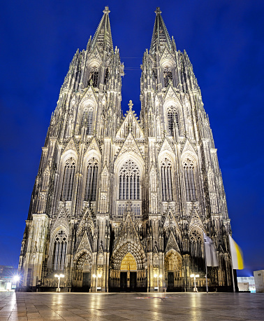 Portal and sculptures on facade of Cologne Cathedral at night, Germany. Composite photo