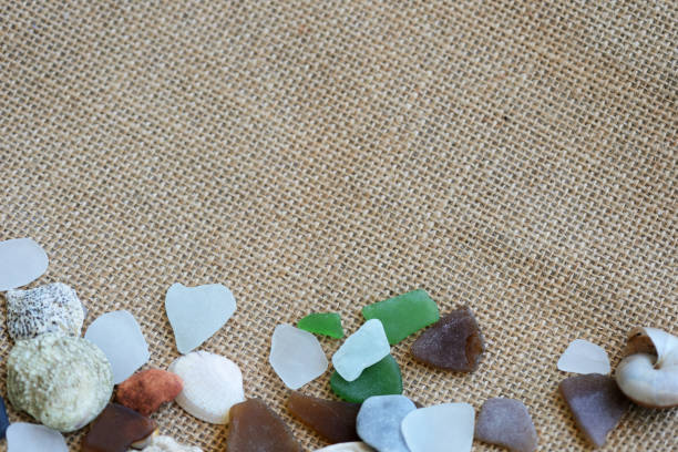 istock Sea glasses, shells and stones on a rough woven background close-up. Vacation concept 1161529535