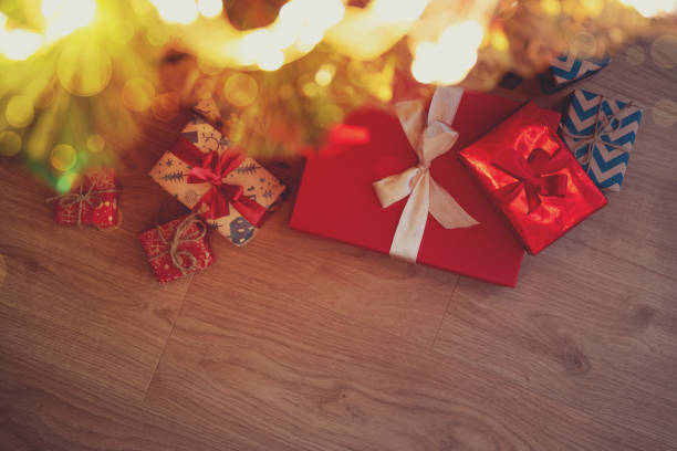 istock Christmas gift boxes wrapped red ribbon lying under Christmas tree against lights background. Christmas or New Year celebration concept. Copy space. Selective focus 1161532640