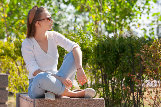 istock Young beautiful woman sitting on bench in park. 1161535011