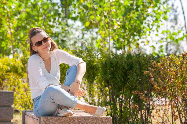 istock Young beautiful woman sitting on bench in park. 1161535083