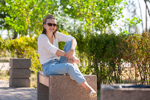 Young beautiful woman sitting on bench in park. Portrait