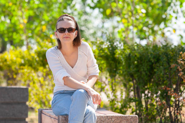 istock Young beautiful woman sitting on bench in park. 1161536986