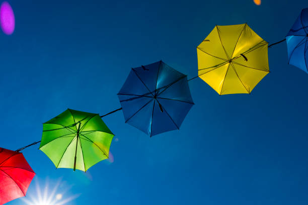 istock colorful umbrella's hanging as garland, against blue sky. 1161544037