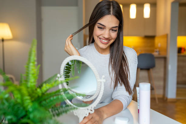 Portrait of a young brunette cosmetics beauty. Portrait of a young brunette cosmetics beauty. Happy young woman looking on mirror. Woman  examining her face in the round mirror. Female putting on moisturizer on her facial skin looking in mirror stock pictures, royalty-free photos & images