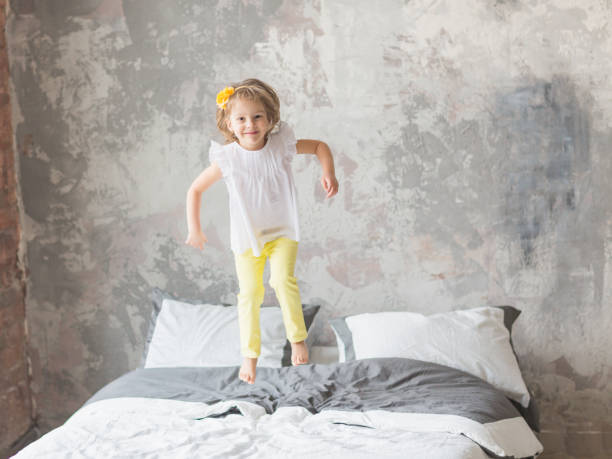 istock Happy child girl having fun jumping on a bed 1161547826