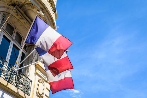 Three french flags decking a building in Paris, France. Low angle view of three french flags decking an haussmannian building in Paris, France, on a sunny summer day. bastille day photos stock pictures, royalty-free photos & images