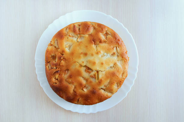 Freshly baked apple pie on a white plate. On a wooden table. View from above.
