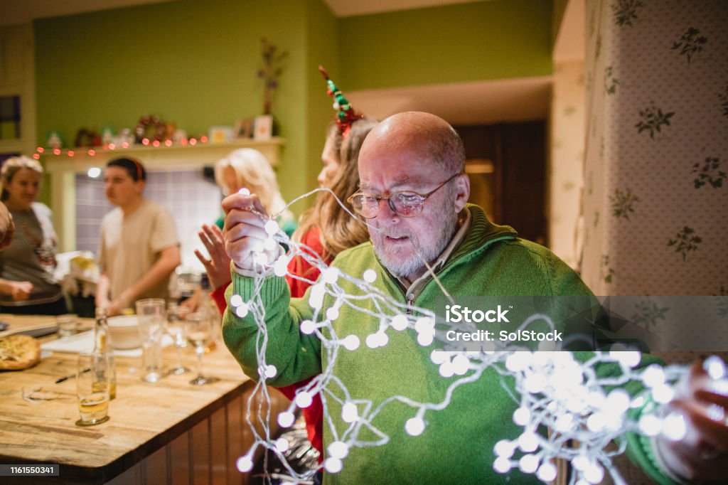 Putting up Christmas Decorations A shot of a senior caucasian man trying to untangle some Christmas lights, he is struggling. Christmas Lights Stock Photo