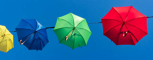 istock colorful umbrella's hanging as garland, against blue sky. 1161550347