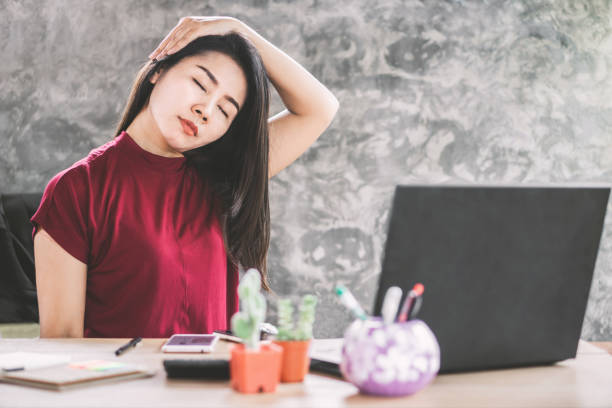 asian female business woman stretching neck to relax muscle of shoulder sitting at office desk - yoga business women indoors imagens e fotografias de stock