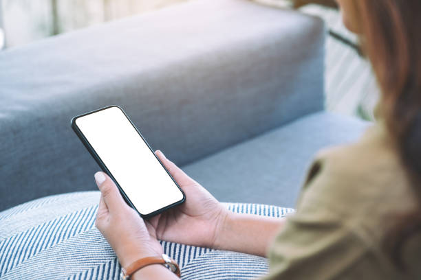 istock a woman holding black mobile phone with blank white desktop screen while sitting in living room 1161552503