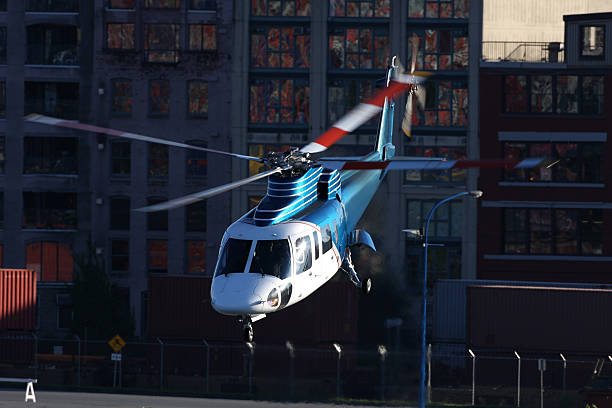 Corporate Helicopter Blue and White corporate sikorsky helicopter taking off with buildings in the background. military private stock pictures, royalty-free photos & images