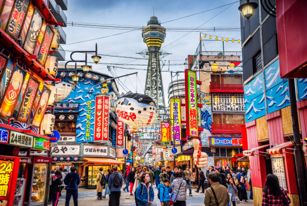 Osaka Tower and view of the neon advertisements in Shinsekai district at dusk, Osaka, Japan view of Osaka Tower and from Shinsekai district at dusk. Osaka, Japan japan sign stock pictures, royalty-free photos & images