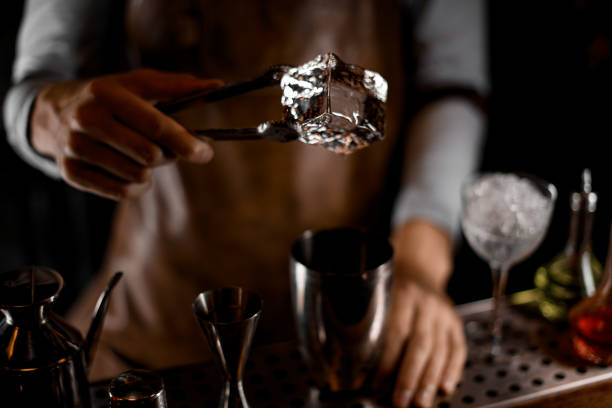 istock Professional bartender putting a big ice cube with tweezers to the steel shaker 1161558057
