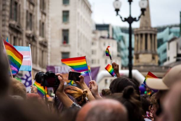 people waving rainbow flag at gay pride parade on city street - gay pride flag fotos imagens e fotografias de stock