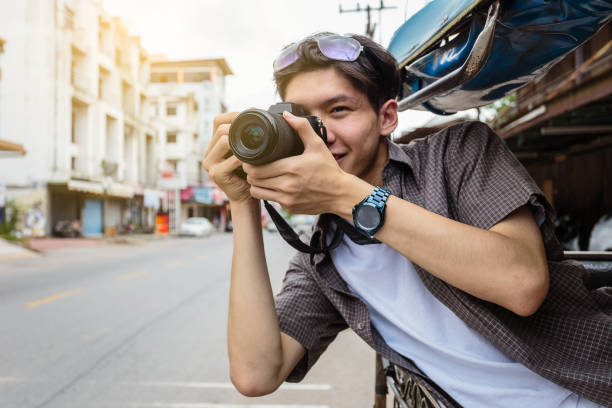 young asian traveller man  taking pictures with camera from local tuk tuk taxi, khonkaen city, thailand - jinrikisha thailand tuk transportation imagens e fotografias de stock