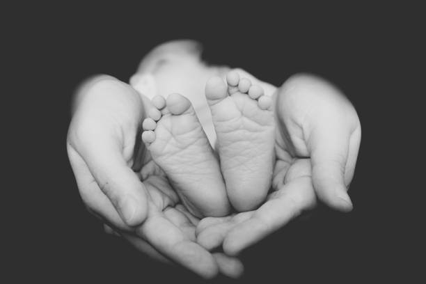 manos de padre cubriendo los pies del recién nacido. - newborn spanish and portuguese ethnicity studio shot lifestyles fotografías e imágenes de stock